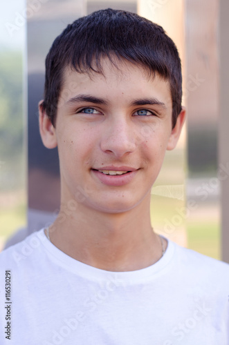 Close up portrait of a young smiling cute teenager with blue eye. © luckykot