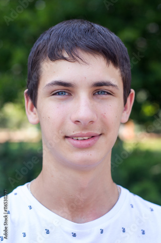 Close up portrait of a young smiling cute teenager with blue eye.