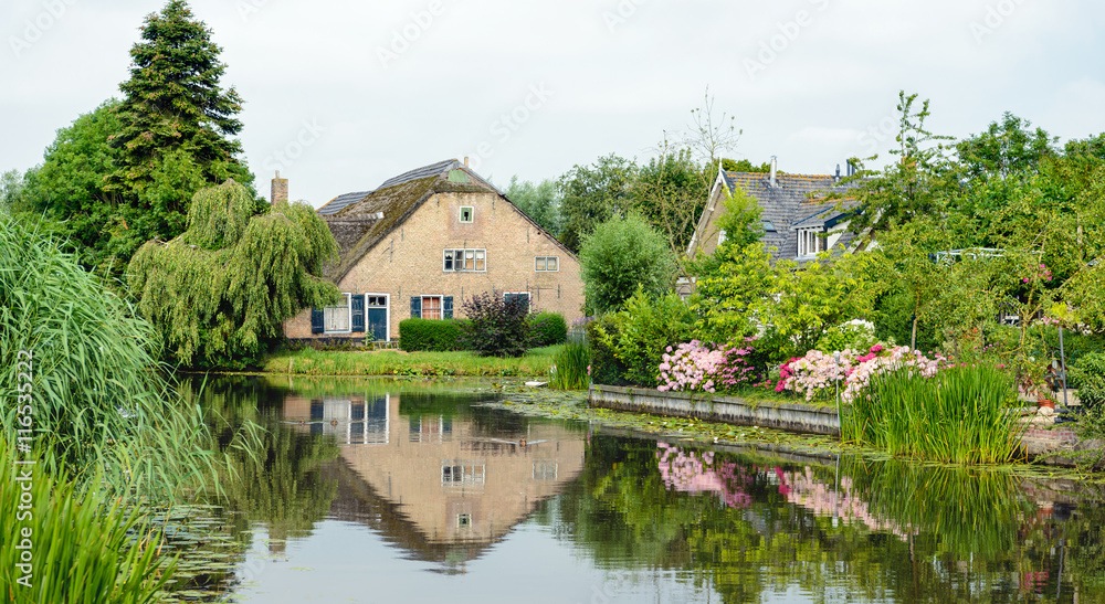 Historic Dutch farm reflected in the mirror smooth water surface