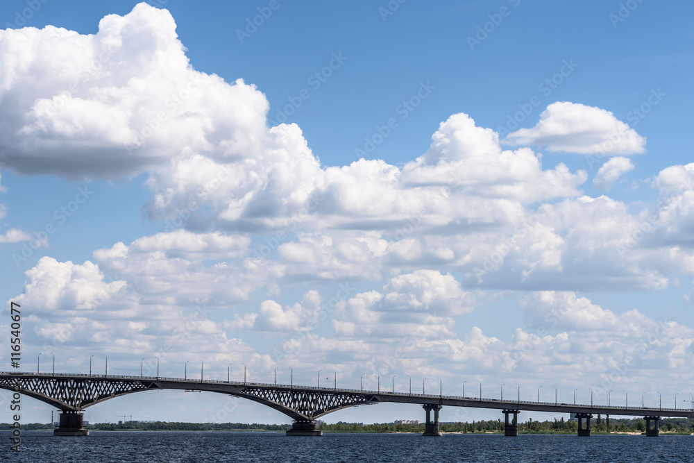 Impressive landscape of the beautiful white clouds in the blue sky above the bridge between the cities of Saratov and Engels through the river Volga Impressive landscape of the beautiful white clouds in the blue sky above the bridge between the cities of Saratov and Engels through the river Volga