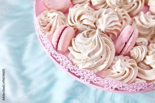 Homemade pink and white meringues on a plate, space for text.