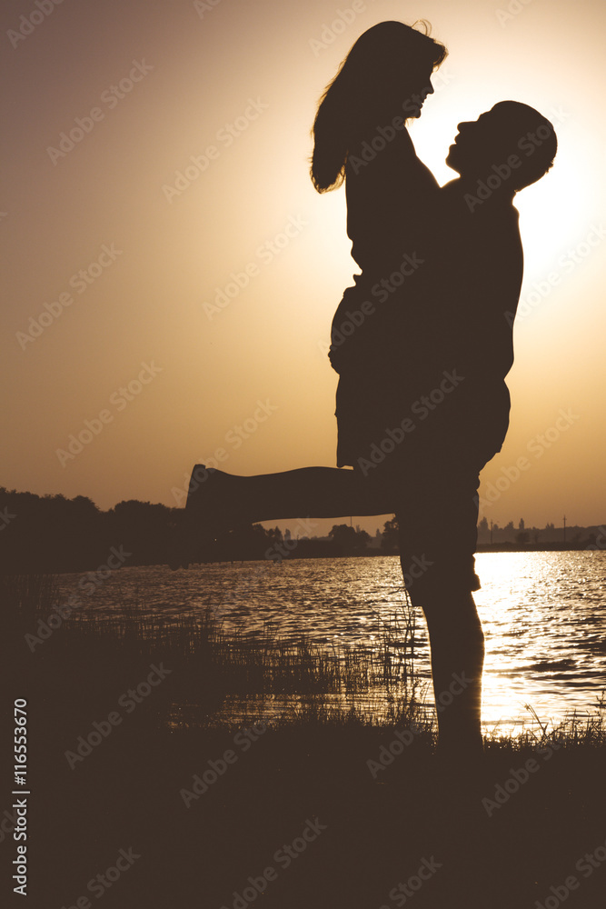 Vintage portrait of love couple hugging on the banks of the river at dawn in the summer
