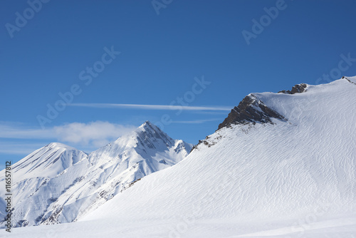 Alpine snow-covered rocks bright winter day.