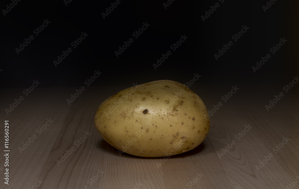 one yellow potato on wooden background , close up one yellow potato on wooden background , close up