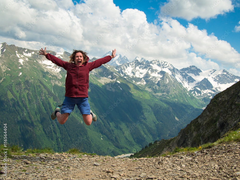 Adult woman jumped up and yells against the backdrop of the mountains of the North Caucasus Adult woman jumped up and yells against the backdrop of the mountains of the North Caucasus