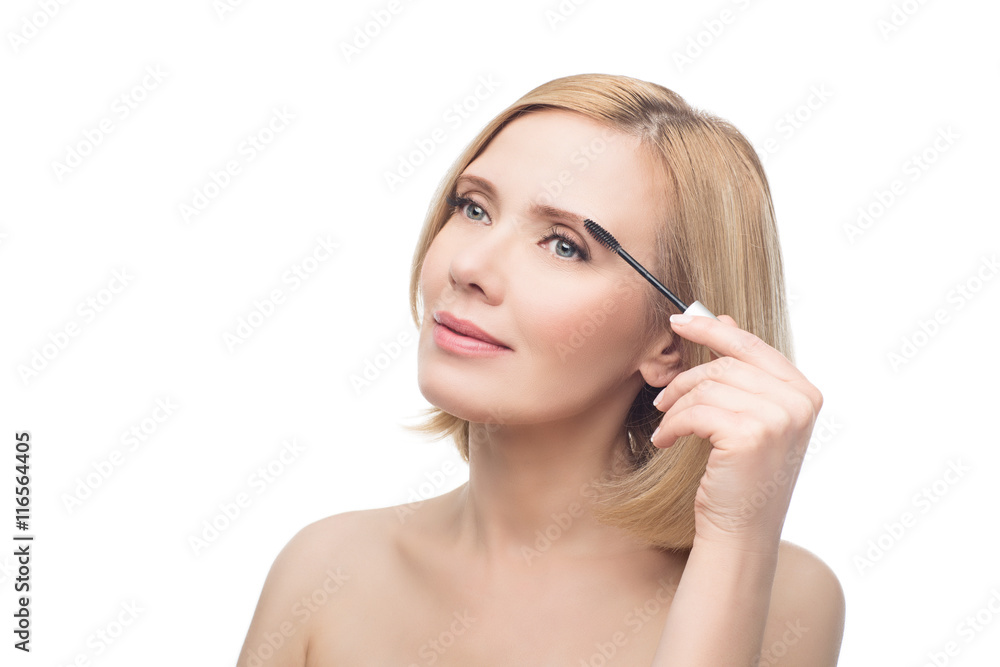Beautiful middle aged woman applying eyebrow gel Beautiful middle aged woman applying eyebrow gel