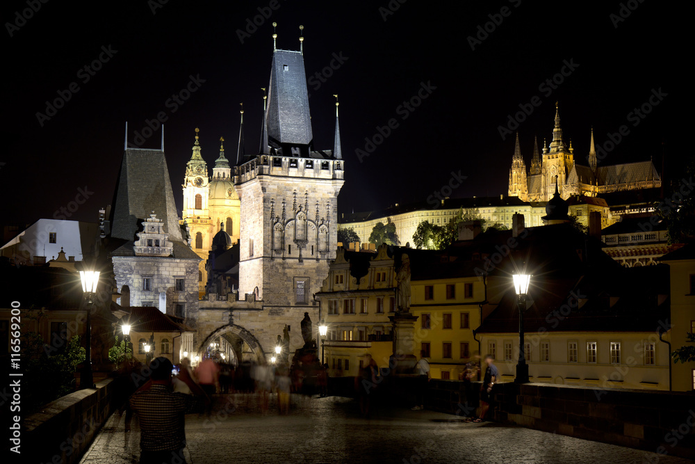 Colorful Prague gothic Castle with St. Nicholas' Cathedral and Bridge Tower from Charles Bridge above the River Vltava in the Night, Czech Republic