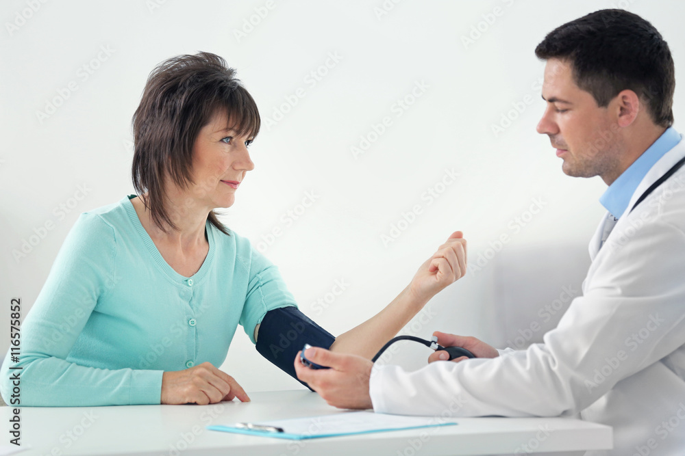 Male doctor measuring woman blood pressure with tonometer Male doctor measuring woman blood pressure with tonometer