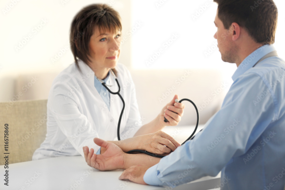 Female doctor measuring man blood pressure with tonometer Female doctor measuring man blood pressure with tonometer