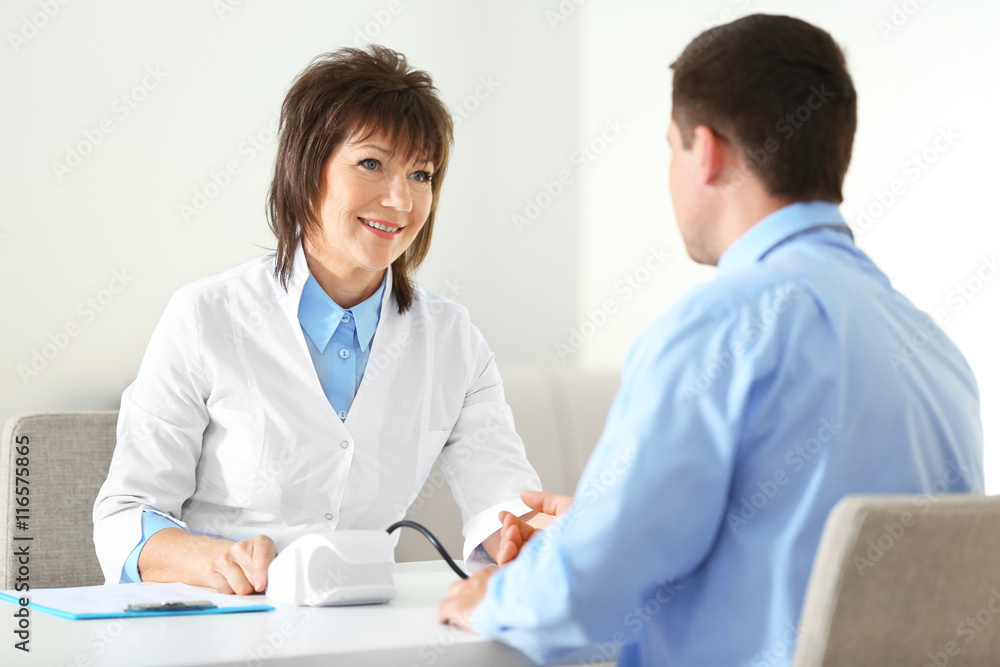 Female doctor measuring man blood pressure in clinic Female doctor measuring man blood pressure in clinic