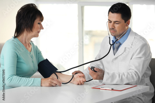 Male doctor measuring woman...