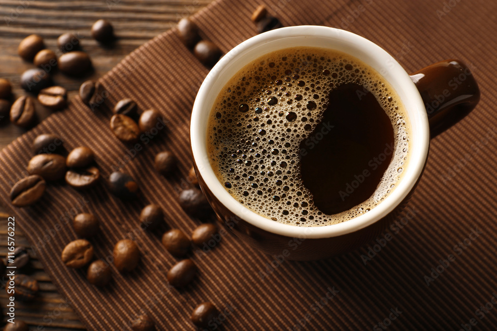 Cup of coffee with beans on wooden table