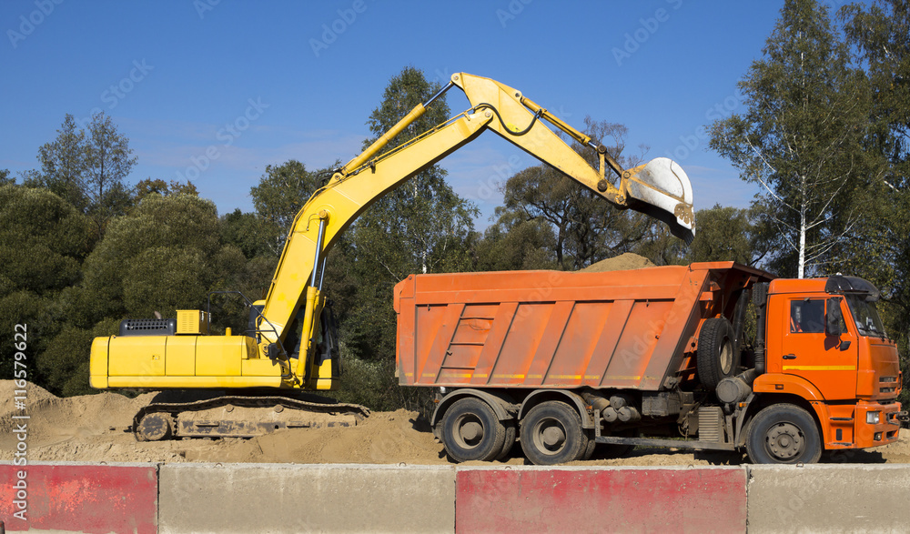 excavator loading dumper truck with sand at construction site excavator loading dumper truck with sand at construction site