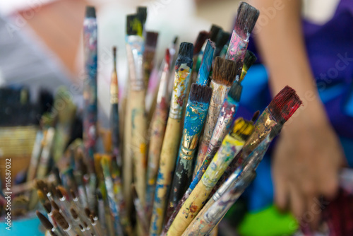 artist paintbrushes in dirty bucket.