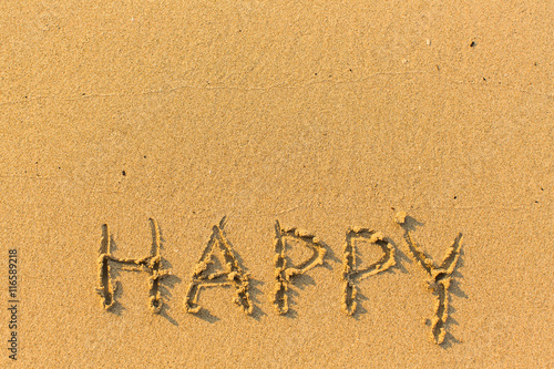 Happy - hand-drawn in gentle sea beach sand.