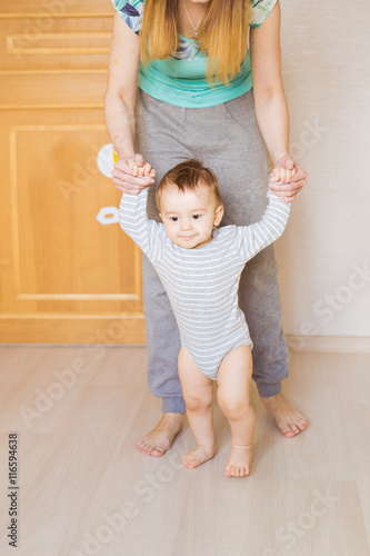 baby taking first steps with mother help