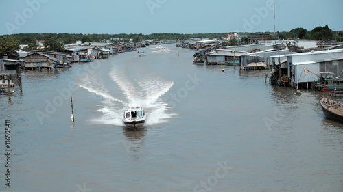 Ca Mau riverside residential with motor boat photo
