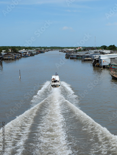 Ca Mau riverside residential with motor boat photo