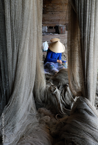 Vietnamese woman sewing fishing net