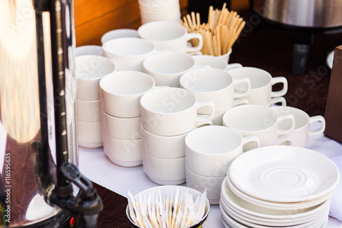 Close up of many empty clean white cups and small plates for coffee or tea and desserts in hotel or restaurant. Coffee brake in office. 