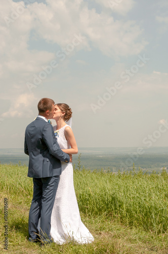 The groom kisses the bride on background of green grass outdoors © Fedoruk