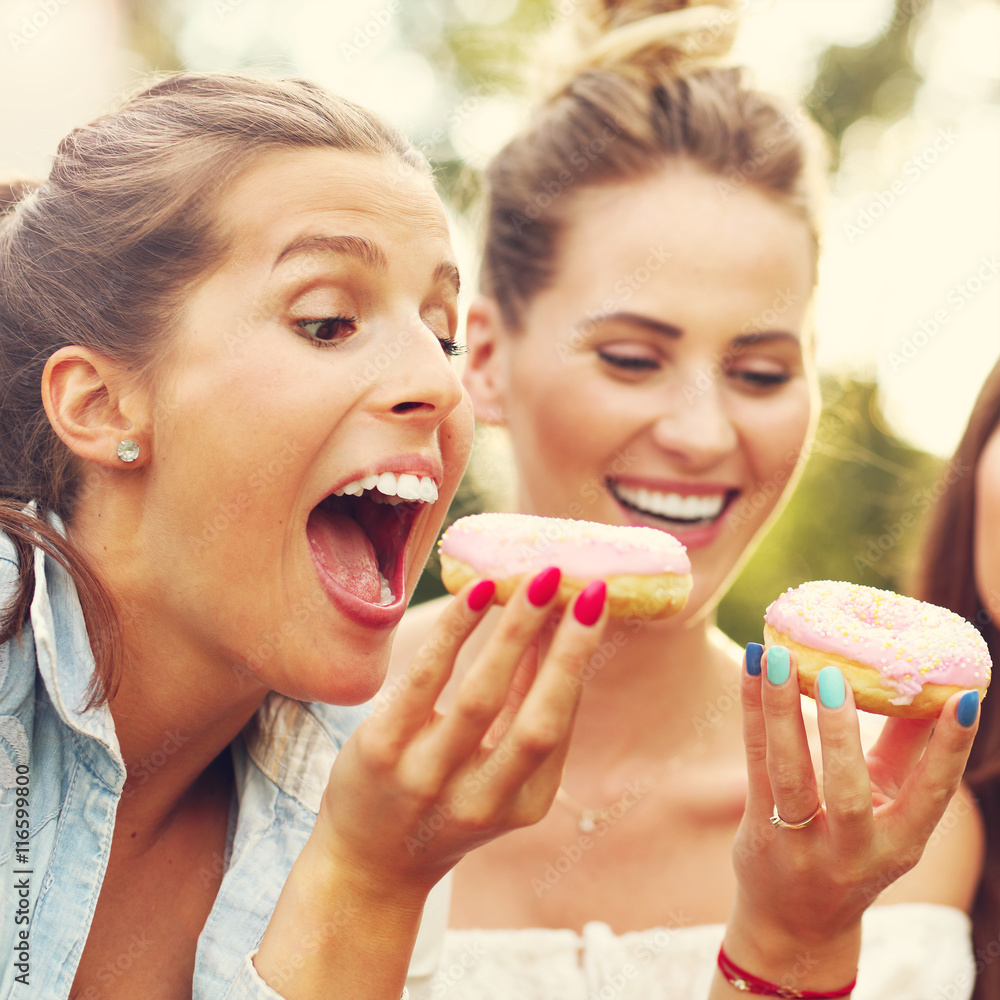Happy group of friends eating donuts outdoors Happy group of friends eating donuts outdoors