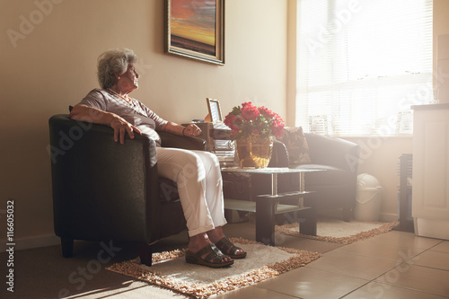 Senior woman sitting alone on a chair at home photo