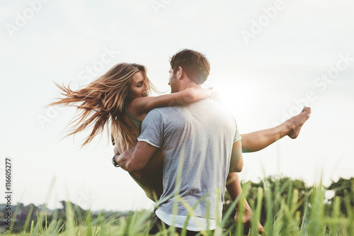 Man carrying girlfriend in  grass field