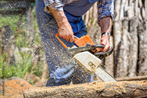 Worker with chainsaw cutting wood