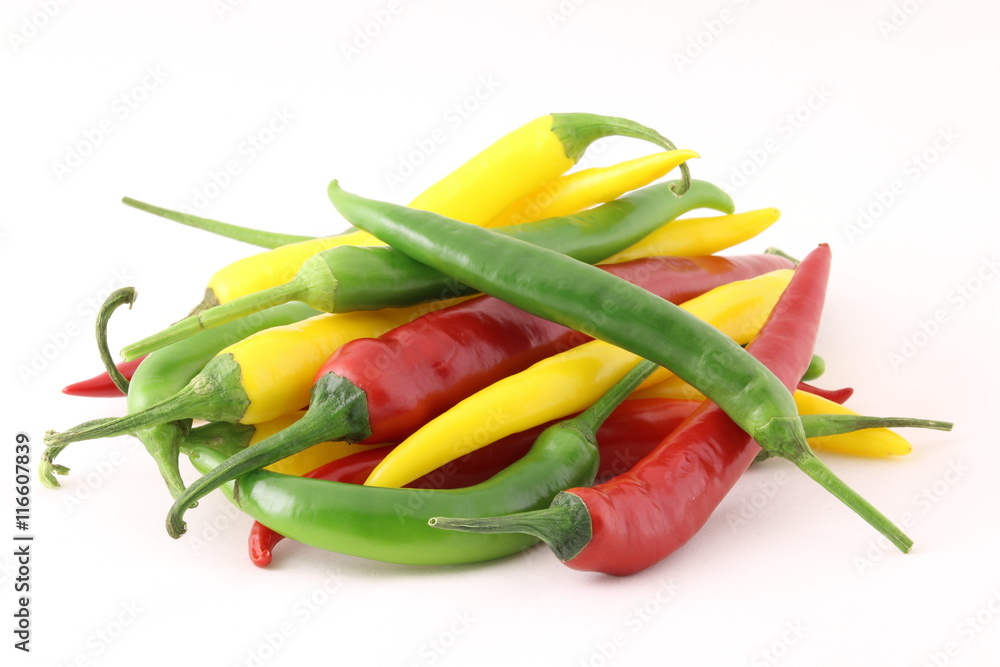 Big pile of chiili peppers in different colors, yellow, green and red, isolated on white; also know as chilli peppers, chille peppers or just chilli