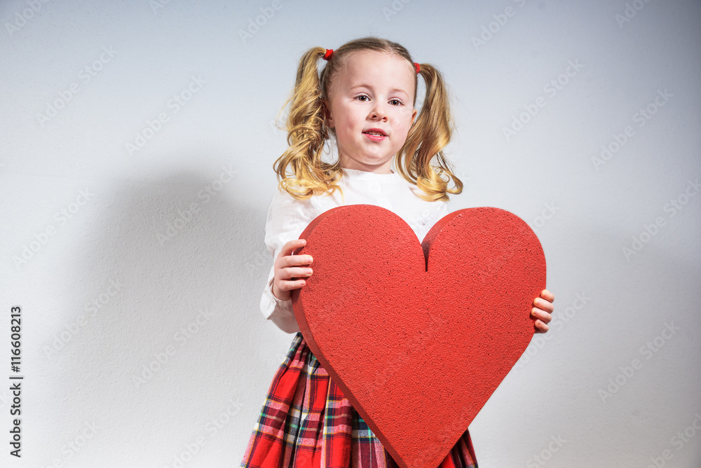 Beautiful smiling blond girl in a school uniform with a big red Beautiful smiling blond girl in a school uniform with a big red