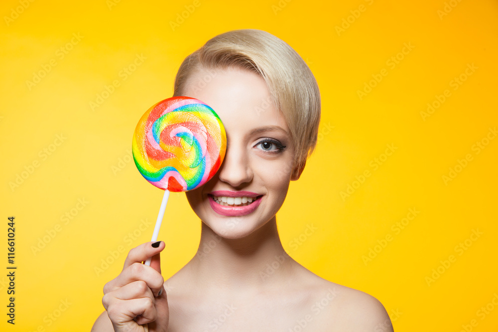 Cheerful blondie with lollipop covering eye