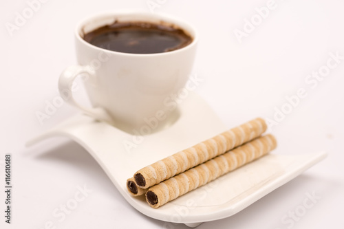 White cup of coffee with wafer chocolate cream rolls