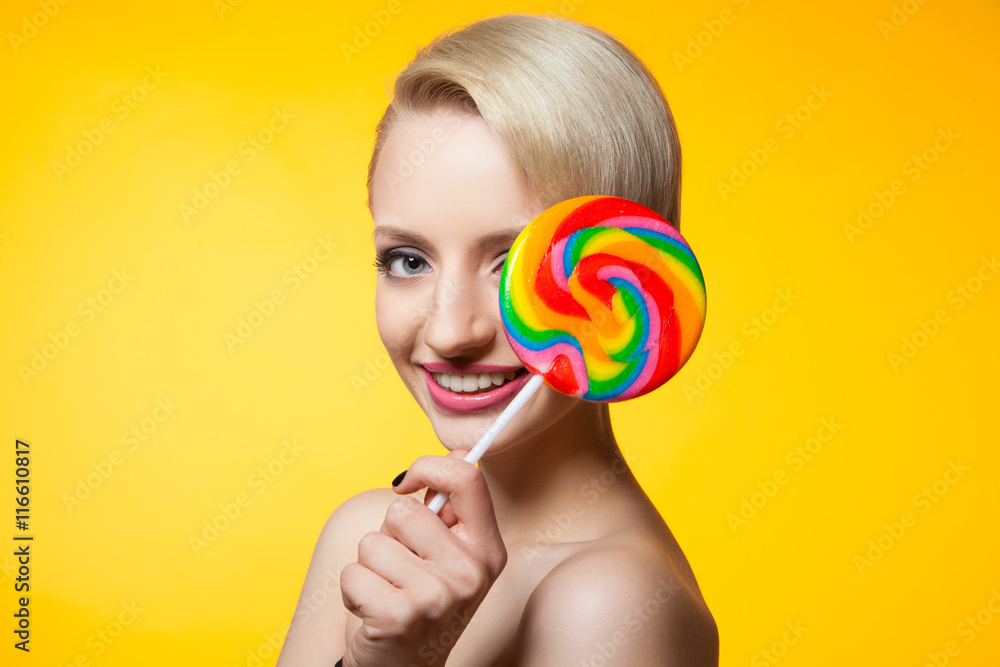 Model covering eye with lollipop and smiling at camera