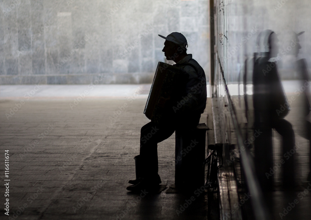 Silhouette of musician with accordion in underpass Silhouette of musician with accordion in underpass