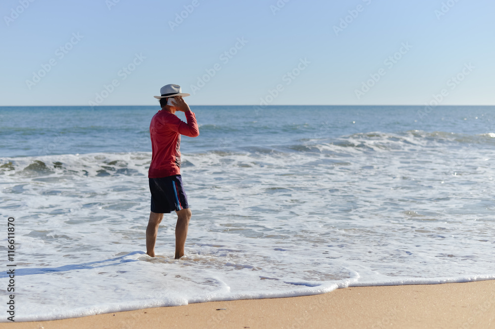 Amazing young male talking on mobile phone, storm wave beach background Amazing young male talking on mobile phone, storm wave beach background