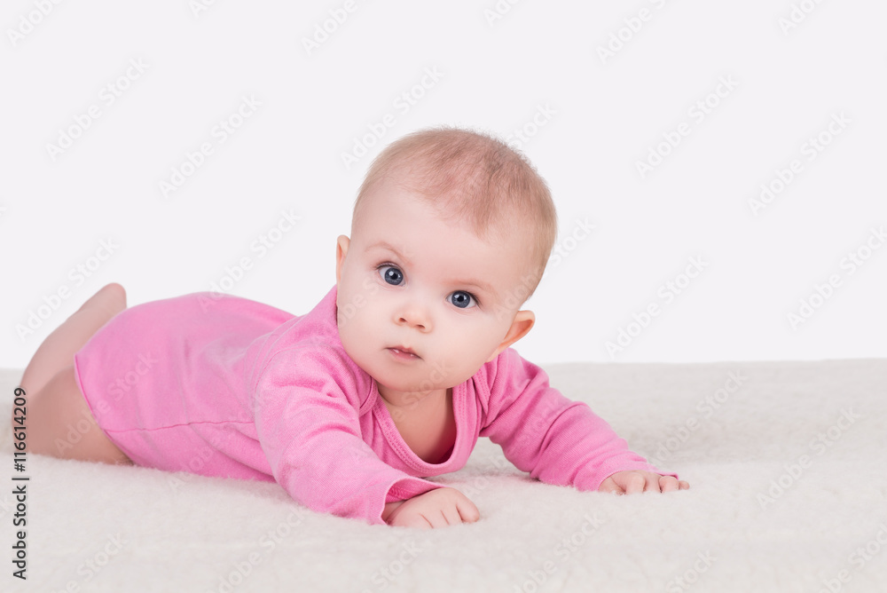cute little baby girl with big blue eyes in pink bodysuit lying on a blanket and try crawling cute little baby girl with big blue eyes in pink bodysuit lying on a blanket and try crawling