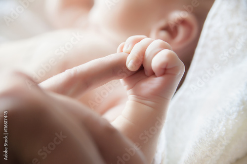 Baby holding a finger of his parent close-up © julenochek