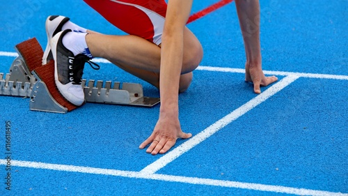 muscular athlete in the starting blocks of a athletic track