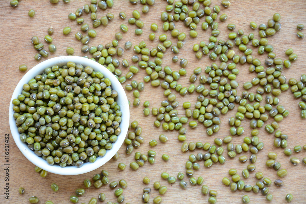 Green bean or mung bean seeds in a cup on a wooden floor. Green bean or mung bean seeds in a cup on a wooden floor.