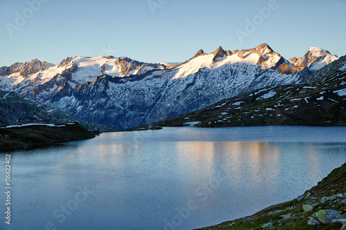 Fototapeta Naklejka Na Ścianę i Meble -  Triebtenseewli, iyllischer Alpensee mit Blick auf verschneite Gebirgskette in der Abendsonne, Wasserspiegelungen