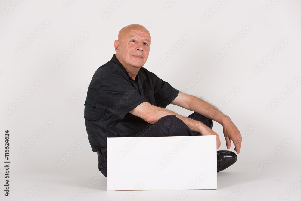 Senior sitzt neben / hinter weißem Schild mit Platz für Text Senior sitzt neben / hinter weißem Schild mit Platz für Text