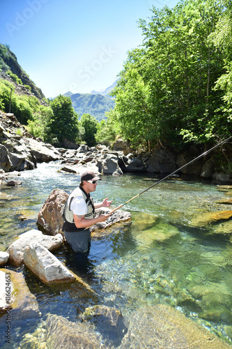 Fisherman trout fishing with bait in mountain river