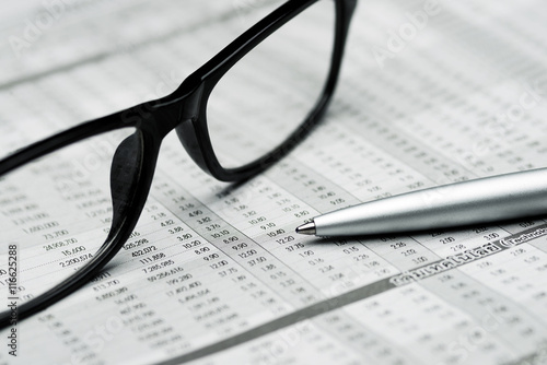 glasses and pen on stock report background