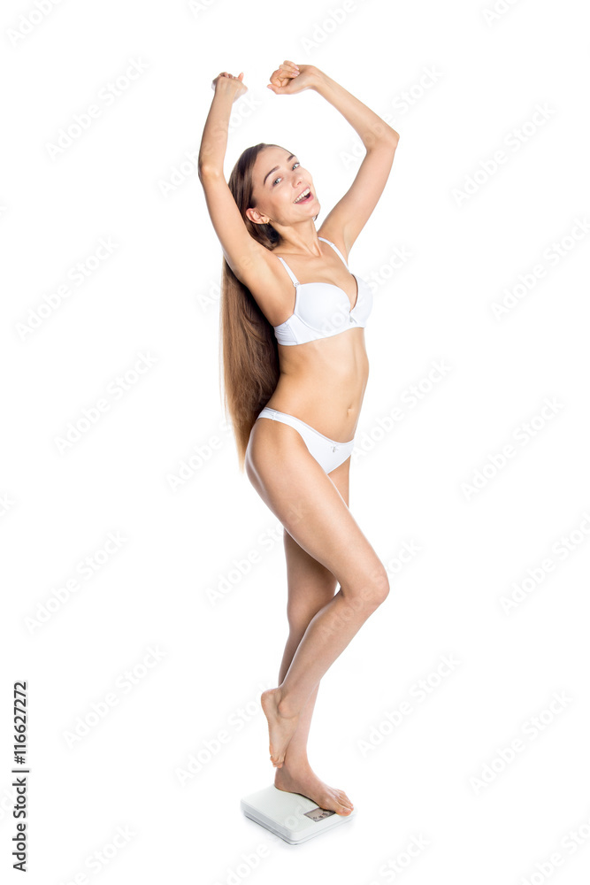Portrait of joyful young Caucasian model with perfect body standing on weighing scale. Pretty person measuring weight and celebrating. Weight loss, dieting, slimming, healthy lifestyle concept. Studio Portrait of joyful young Caucasian model with perfect body standing on weighing scale. Pretty person measuring weight and celebrating. Weight loss, dieting, slimming, healthy lifestyle concept. Studio