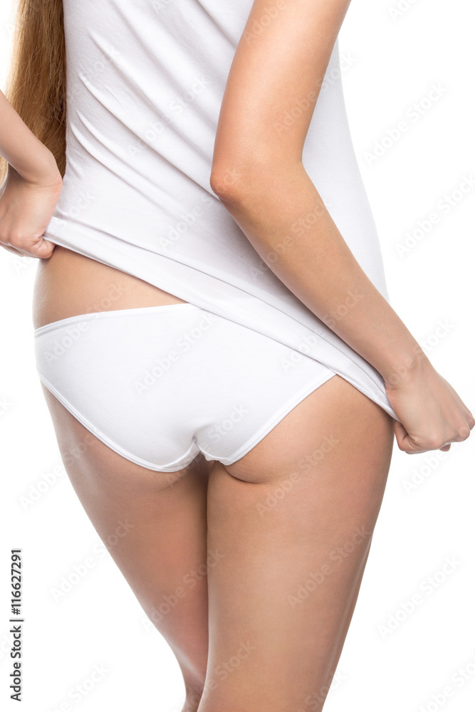 Foto Stock Back view closeup. Pretty model with perfect butt shape pulling  tank top over panties. Beautiful attractive person wearing white color set  of underwear. Dieting, healthy lifestyle concept. Studio shot
