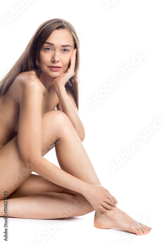 Portrait of young beautiful Caucasian model with long legs sitting against white background. Pretty person with perfect body posing. Studio image. Closeup. Weight loss, healthy lifestyle concept