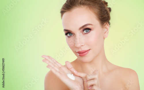 happy young woman with moisturizing cream on hand