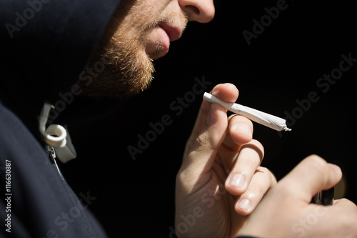 close up of addict lighting up marijuana joint