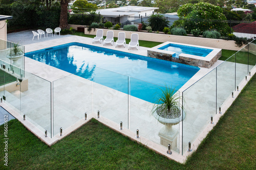 Modern swimming pool covered with glass panels beside a lawn